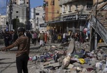 فلسطينيون يتجمعون أمام مبنى قصفه الاحتلال في مخيم النصيرات للاجئين بقطاع غزة - AP