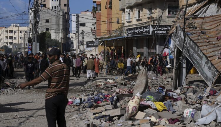 فلسطينيون يتجمعون أمام مبنى قصفه الاحتلال في مخيم النصيرات للاجئين بقطاع غزة - AP