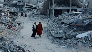 فلسطينيون يسيرون وسط أنقاض المباني التي دمرتها غارة إسرائيلية في خان يونس بجنوب قطاع غزة (رويترز)