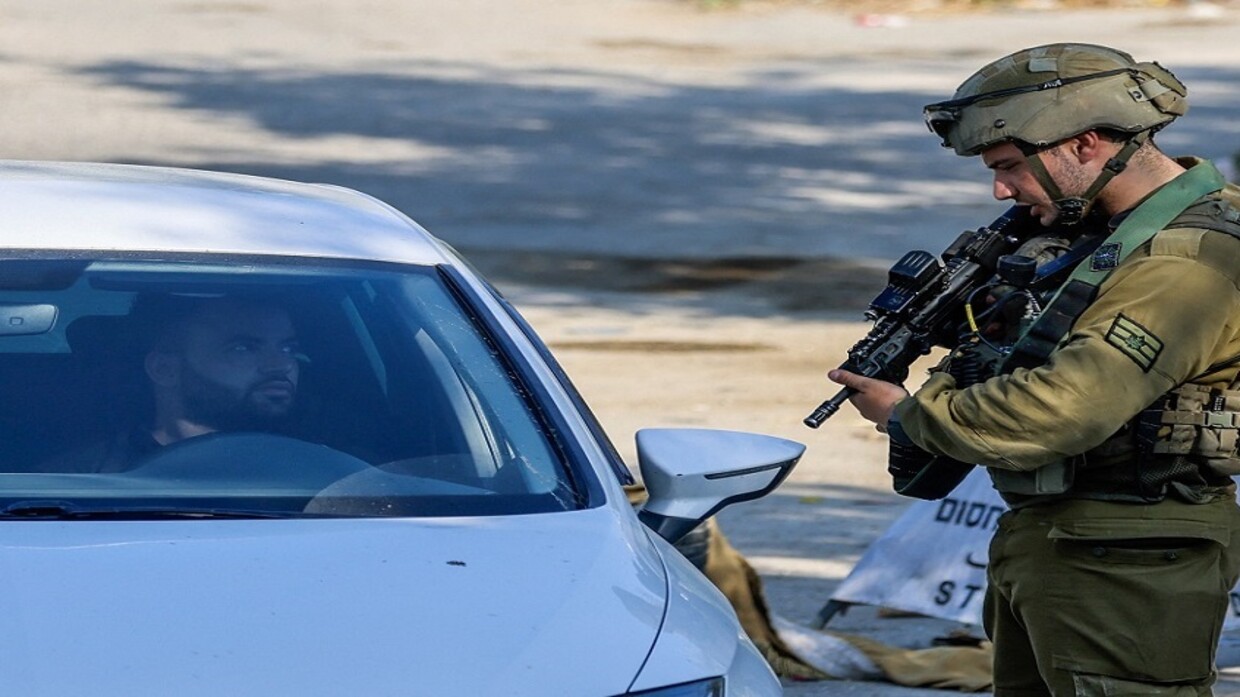 جندي إسرائيلي يوقف سيارة فلسطينية على أحد الحواجز / wafa.ps