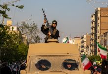 امرأة تحمل بندقية أثناء ركوبها مركبة عسكرية خلال مظاهرة في طهران الجمعة. / Gettyimages.ru