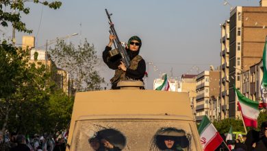امرأة تحمل بندقية أثناء ركوبها مركبة عسكرية خلال مظاهرة في طهران الجمعة. / Gettyimages.ru